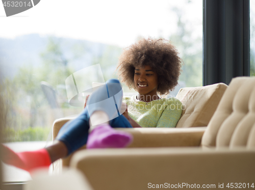 Image of young african american woman at home using digital tablet