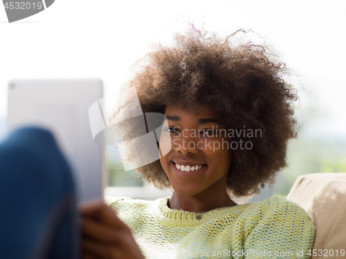 Image of young african american woman at home using digital tablet