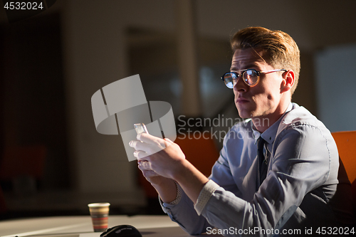 Image of man using mobile phone in dark office