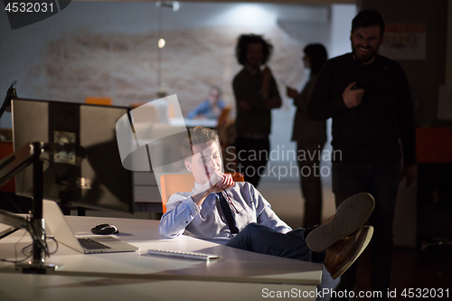 Image of businessman sitting with legs on desk at office