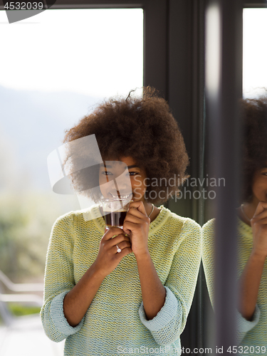 Image of African American woman drinking coffee looking out the window