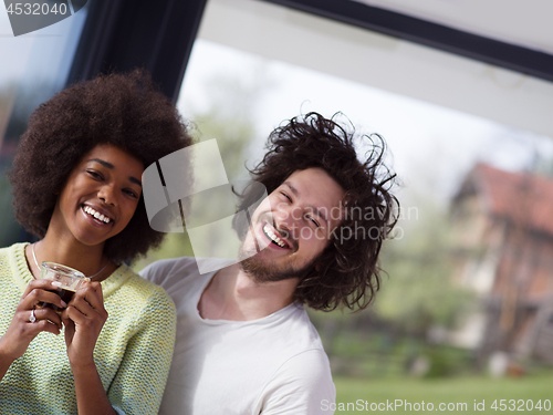 Image of happy multiethnic couple relaxing at modern home indoors