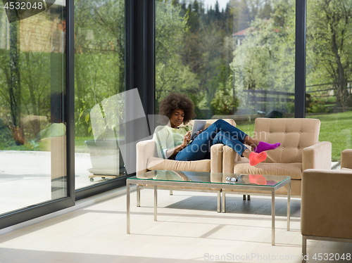 Image of young african american woman at home using digital tablet