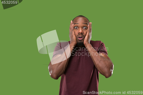 Image of The young attractive man looking suprised isolated on green