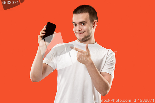 Image of The happy man showing at empty screen of mobile phone against orange background.