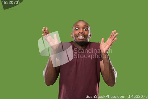Image of The young attractive man looking suprised isolated on green