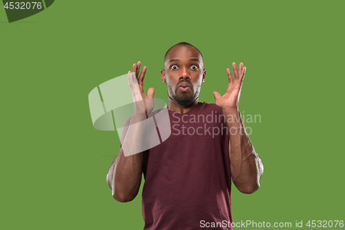 Image of The young attractive man looking suprised isolated on green
