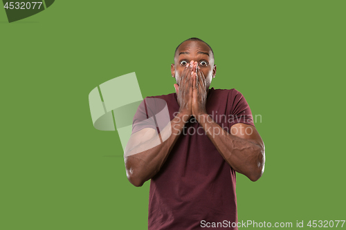 Image of The young attractive man looking suprised isolated on green