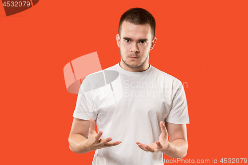 Image of The young emotional angry man on orange studio background