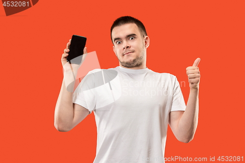 Image of The happy man showing at empty screen of mobile phone against orange background.