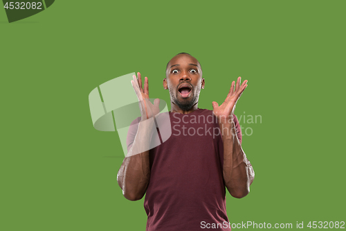 Image of The young attractive man looking suprised isolated on green