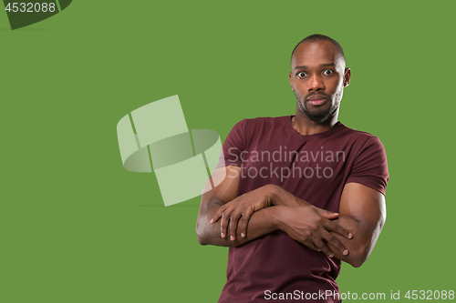 Image of The young attractive man looking suprised isolated on green