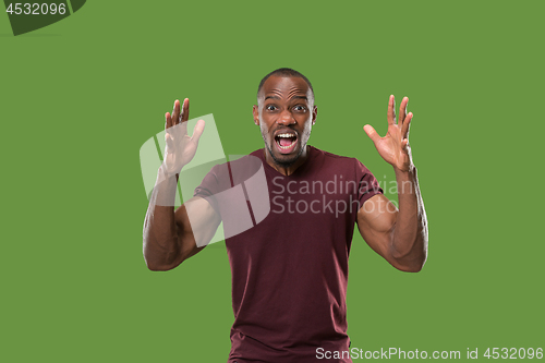 Image of The young emotional angry man screaming on green studio background