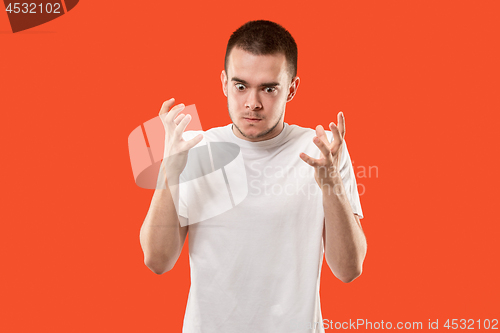 Image of The young emotional angry man on orange studio background