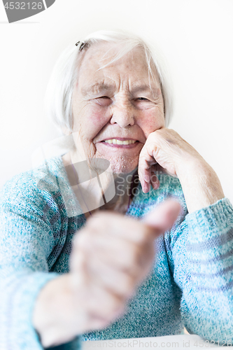 Image of Happy 96 years old elderly woman giving a thumb up and looking at camera.