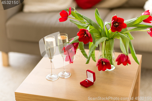 Image of diamond ring, champagne and flowers on table