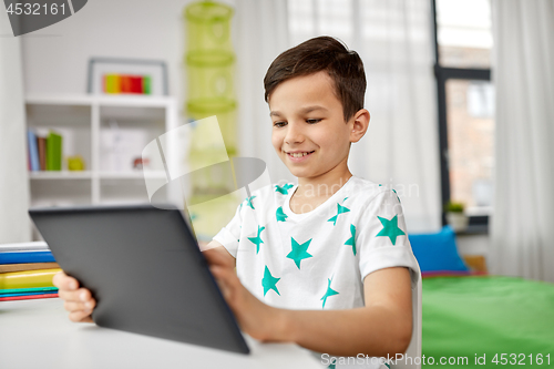 Image of student boy with tablet pc and notebook at home