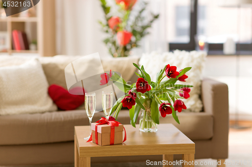 Image of gift box, champagne glasses and flowers on table