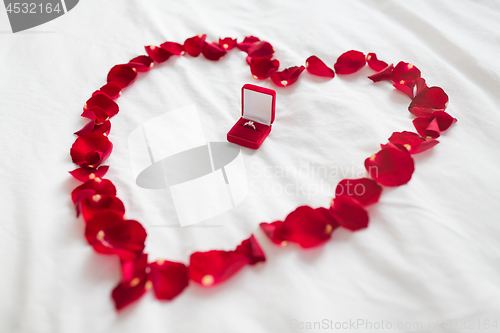 Image of heart made of petals and diamond ring in gift box