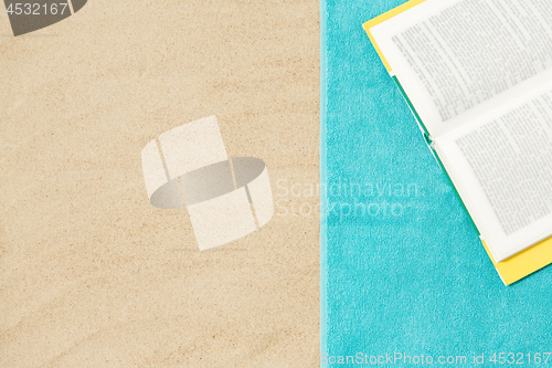 Image of book on beach towel on sand