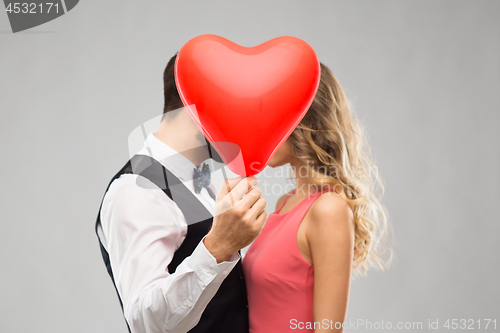 Image of couple hiding behind red heart shaped balloon