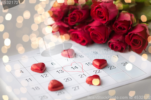 Image of close up of calendar, heart, candies and red roses