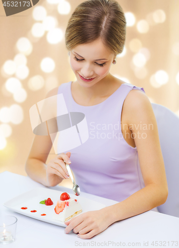 Image of smiling young woman eating dessert at restaurant