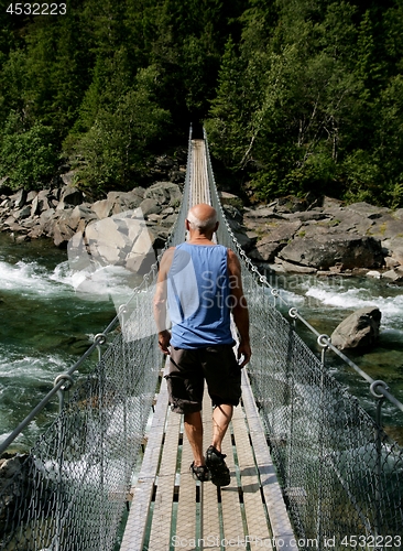 Image of Man walking on a suspension bridge