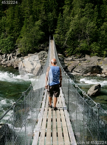 Image of Man walking on a suspension bridge