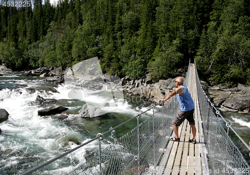 Image of Man standing on a suspension bridge