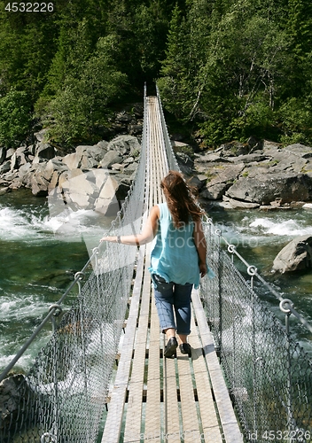 Image of Woman walking on a suspension bridge