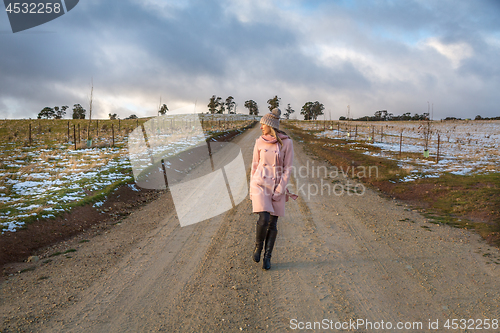 Image of Woman walking down a country road in winter