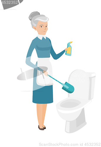 Image of Senior caucasian cleaner cleaning toilet bowl.