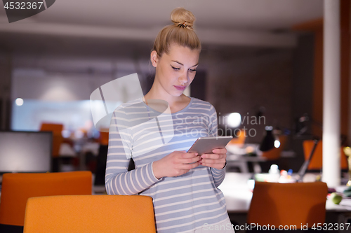 Image of woman working on digital tablet in night office