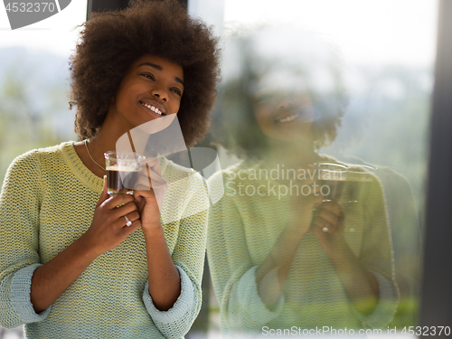 Image of African American woman drinking coffee looking out the window