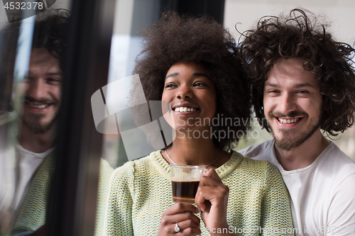 Image of happy multiethnic couple relaxing at modern home indoors