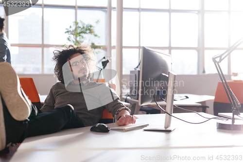 Image of businessman sitting with legs on desk