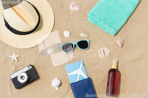 Image of travel tickets, camera and hat on beach sand