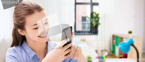 Image of smiling girl messaging on smartphone at home