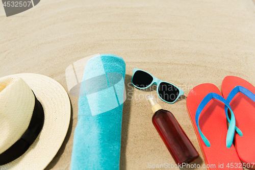 Image of straw hat, flip flops and sunglasses on beach sand