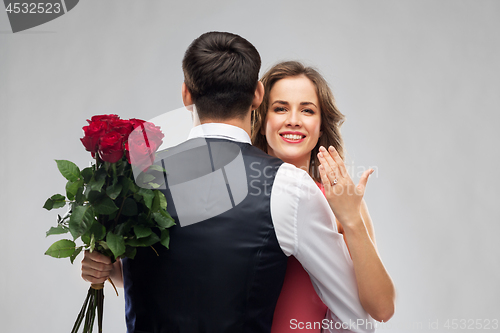 Image of woman with engagement ring and roses hugging man