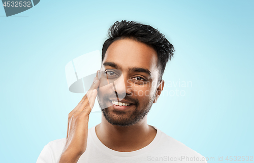 Image of smiling indian man touching his face