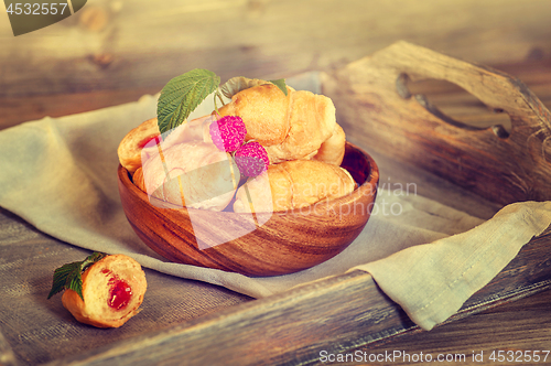 Image of Croissants with raspberries on a wooden tray. The concept of a wholesome breakfast.