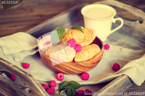 Image of Croissants with raspberries on a wooden tray. The concept of a wholesome breakfast.