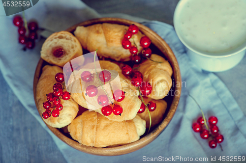 Image of Croissants with currant berries on a wooden tray.
