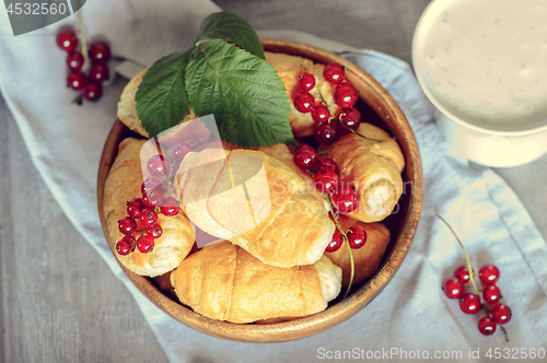 Image of Croissants with currant berries on a wooden tray. The concept of a wholesome breakfast.