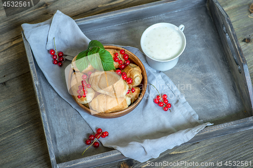 Image of Croissants with currant berries on a wooden tray. The concept of a wholesome breakfast.