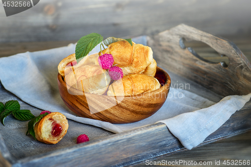 Image of Croissants with raspberries on a wooden tray. The concept of a wholesome breakfast.