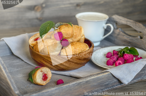 Image of Croissants with raspberries on a wooden tray. The concept of a wholesome breakfast.