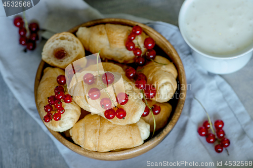 Image of Croissants with currant berries on a wooden tray. The concept of a wholesome breakfast.